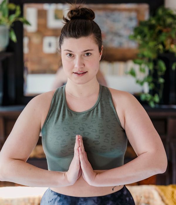 Serene woman practicing yoga in a dark room with golden light.